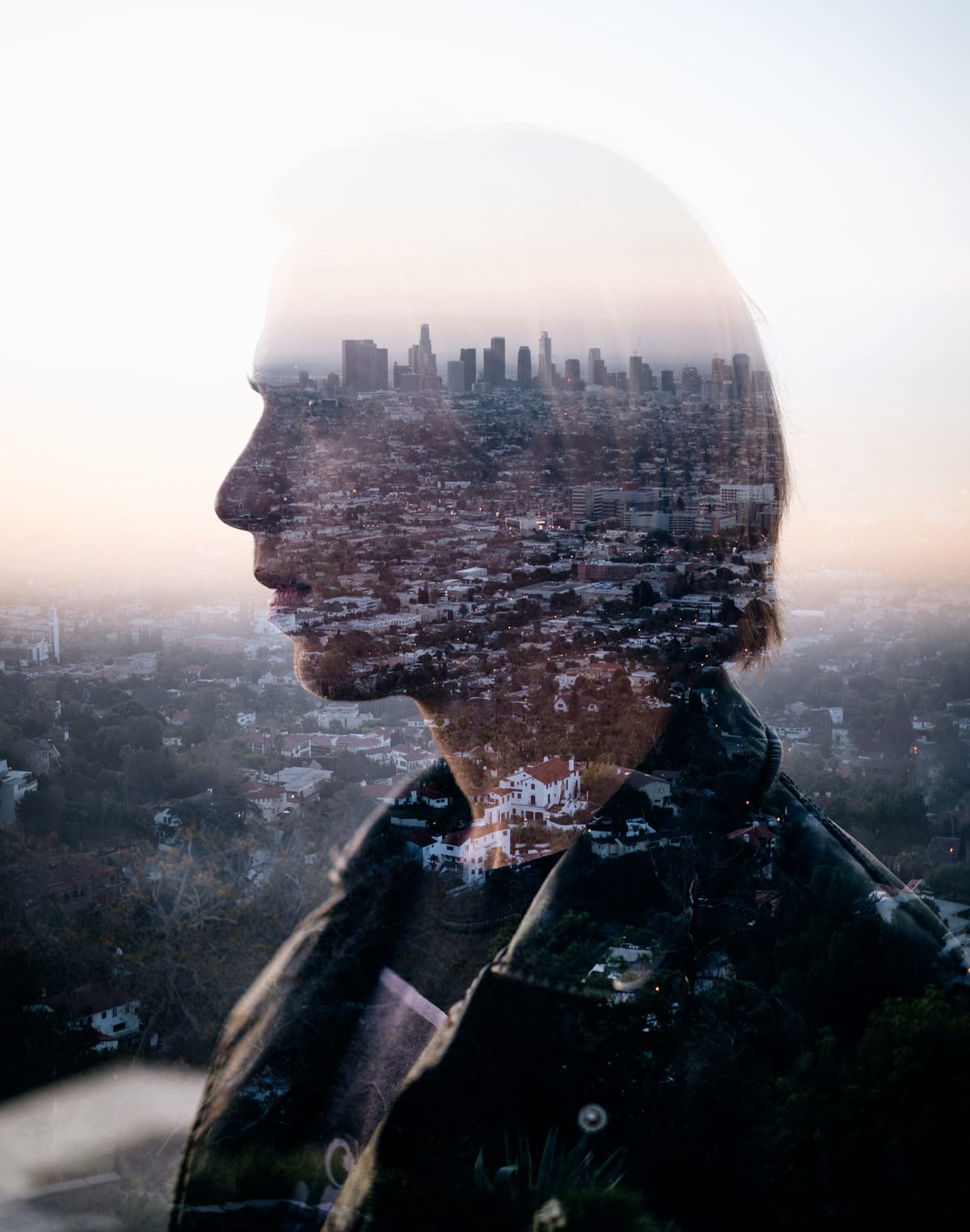 City landscape reflected over a person's face. They are wearing a leather jacket and t-shirt.