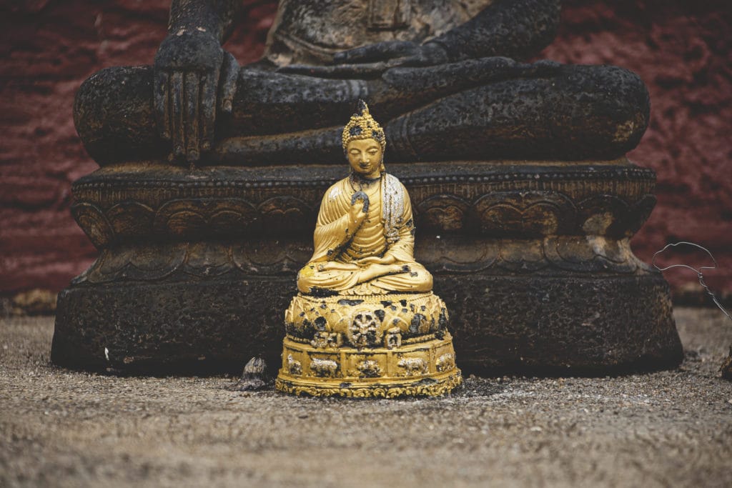 A gold statue in front of meditation mats.