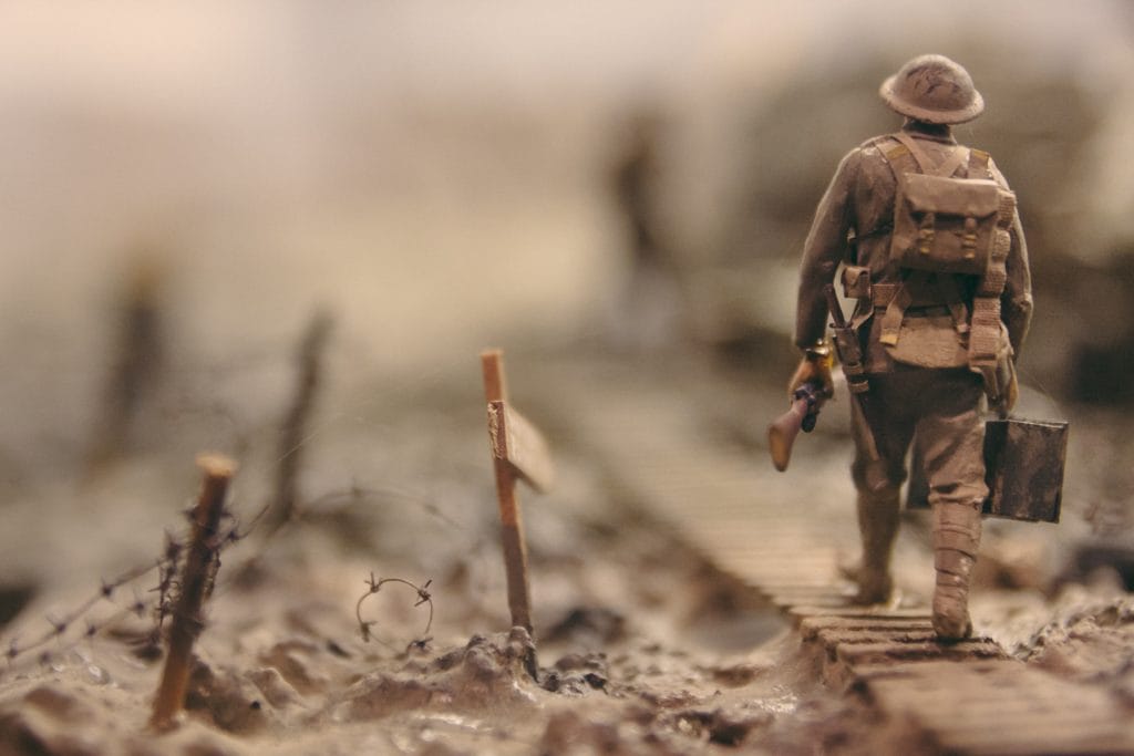 A soldier in the war. He is holding a gun and walking on a wooden platform.