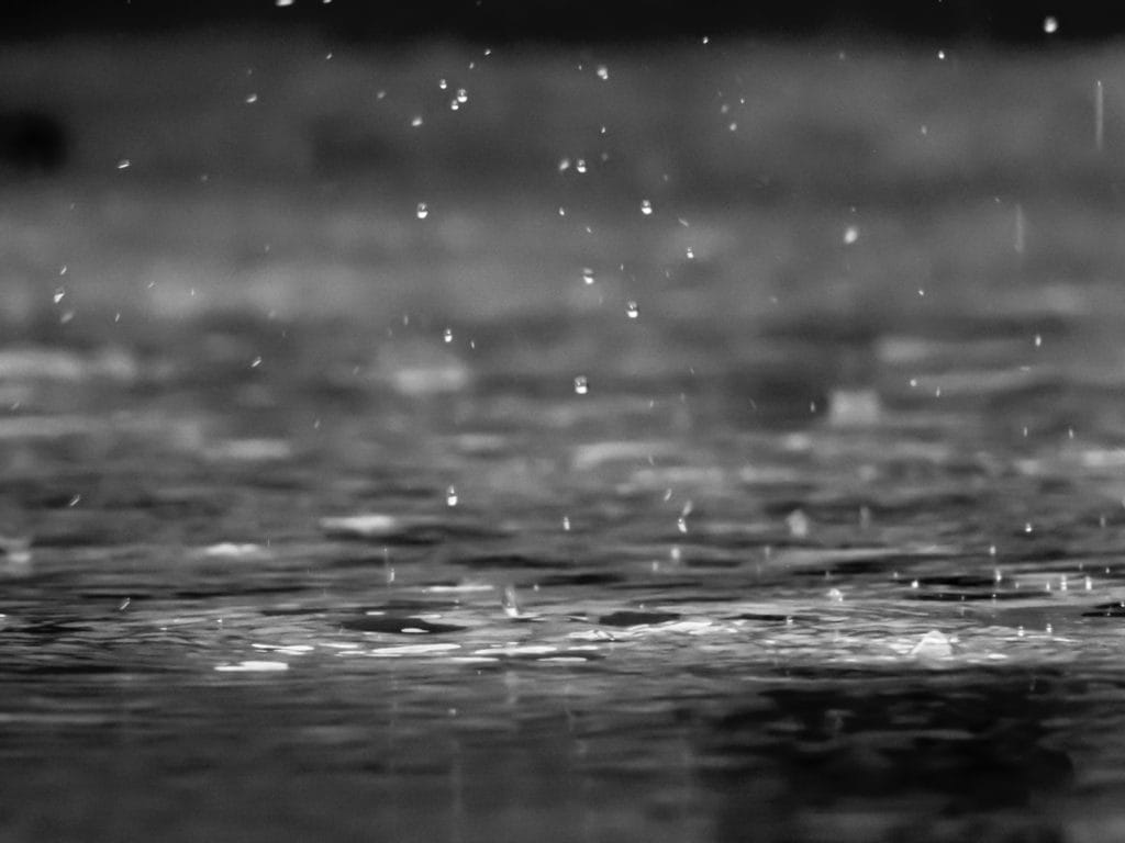 A black and white photo of raindrops hitting a body of water.