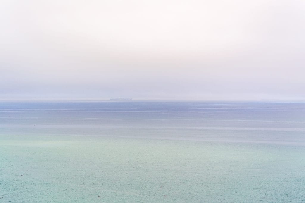 The sky and the ocean. The photo has a light periwinkle to seafoam green gradient.