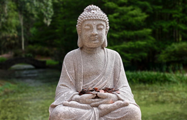 Buddha statue covered in offering coins.