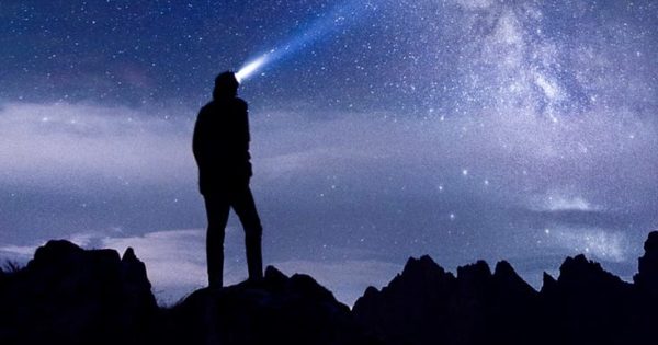 Man with headlamp looking into space.