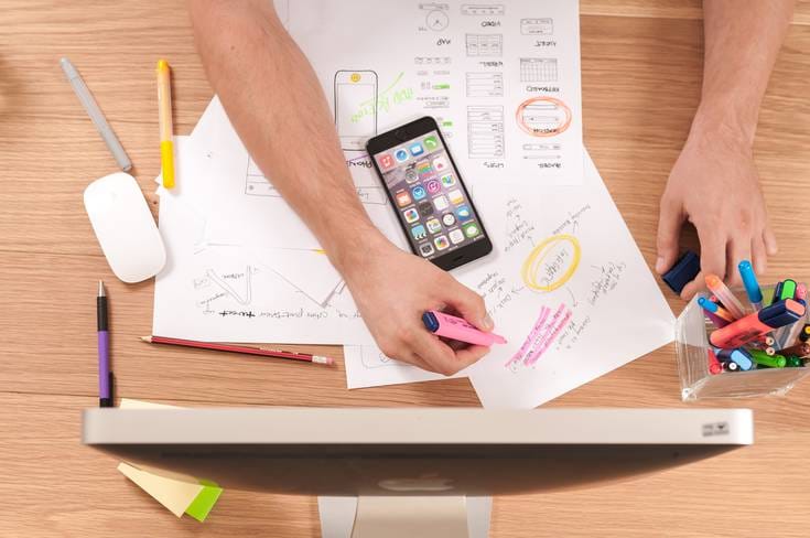 Man highlighting paper on a cluttered desk.