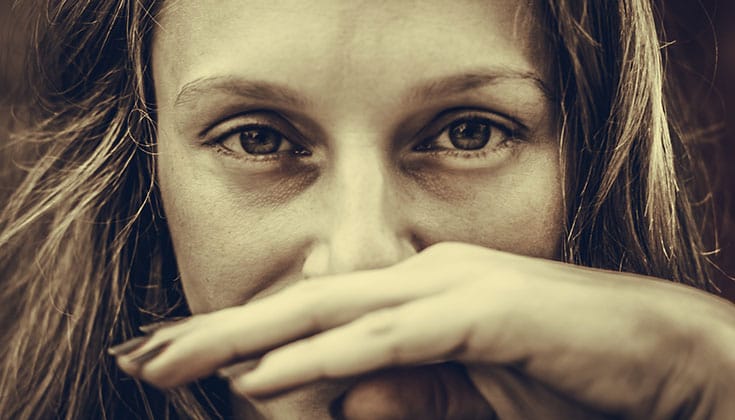 Woman holding hand over mouth.
