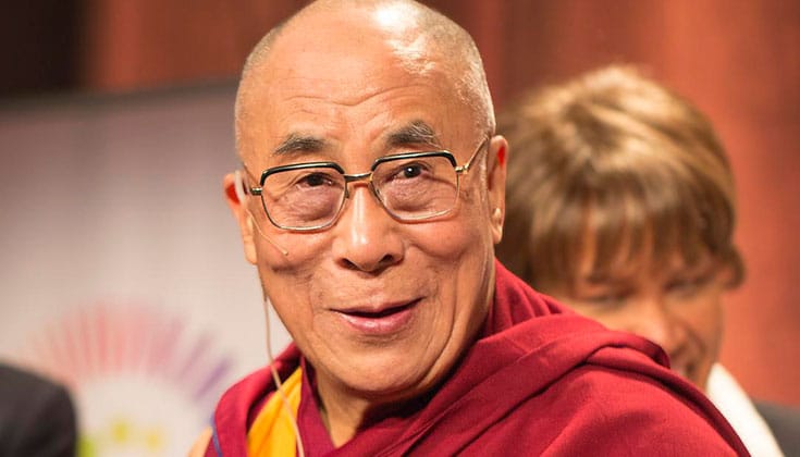 Dalai Lama smiling. He is wearing red robes and glasses.