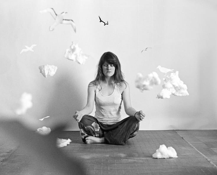 Woman meditating surrounded by clouds.