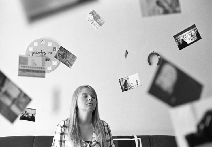 Woman sitting surrounded by pictures.