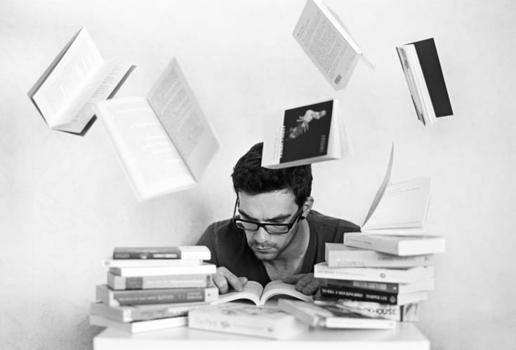 Man reading surrounded by books.