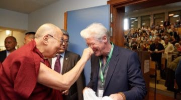 The Dalai Lama squeezes Richard Gere's nose.