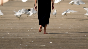Woman walking barefoot on pier.