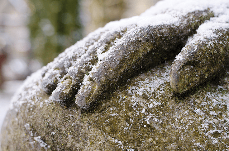 Hand of a Buddha statue covered in snowflakes. Photo by David Gabriel Fischer.