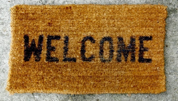A straw mat that says "welcome" in black text.