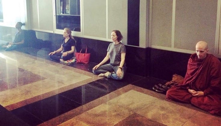 People meditating in a building lobby.