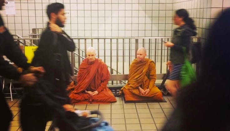 Two monks meditating in a New York subway station.