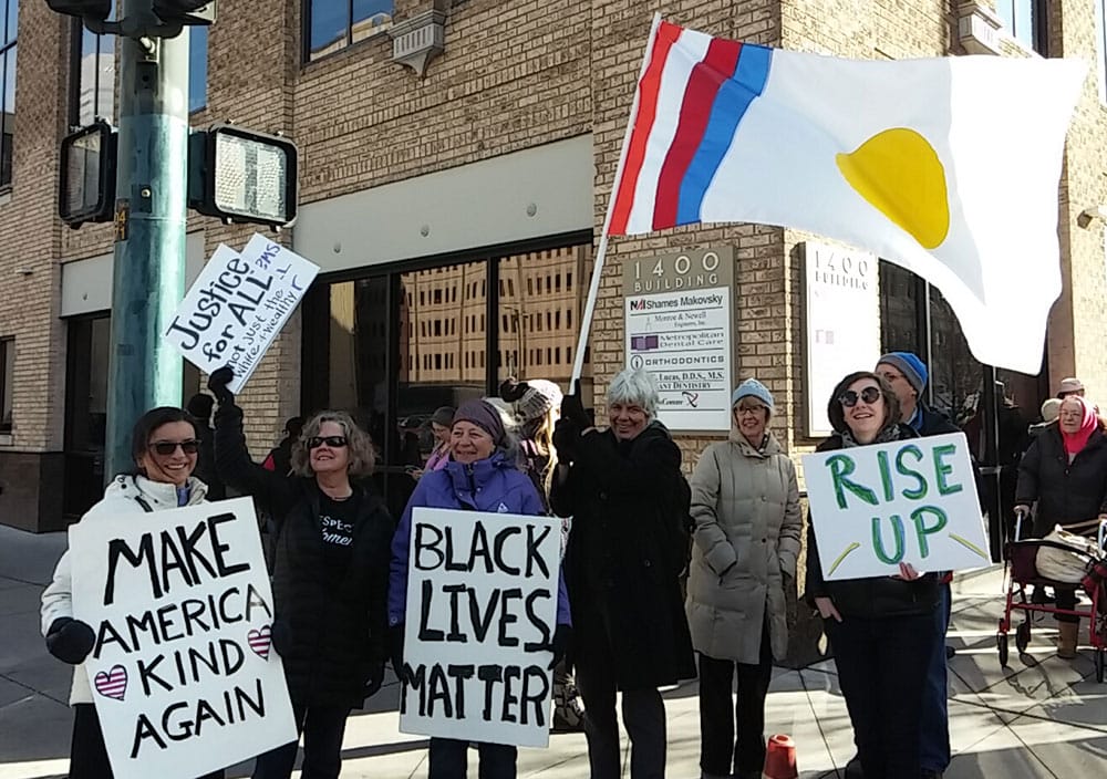 Michele O'Donoghue holds a "Make America Kind Again," sign while Karen from Albuquerque, NM carries the Shambhala flag. Photo by Mark O'Donoghue.