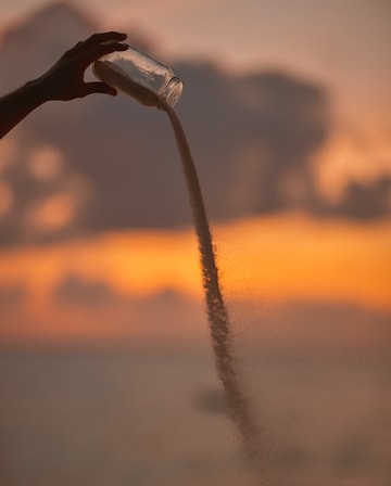 Jar of sand pouring out at sunset.