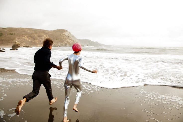 Bride and groom running into the ocean.