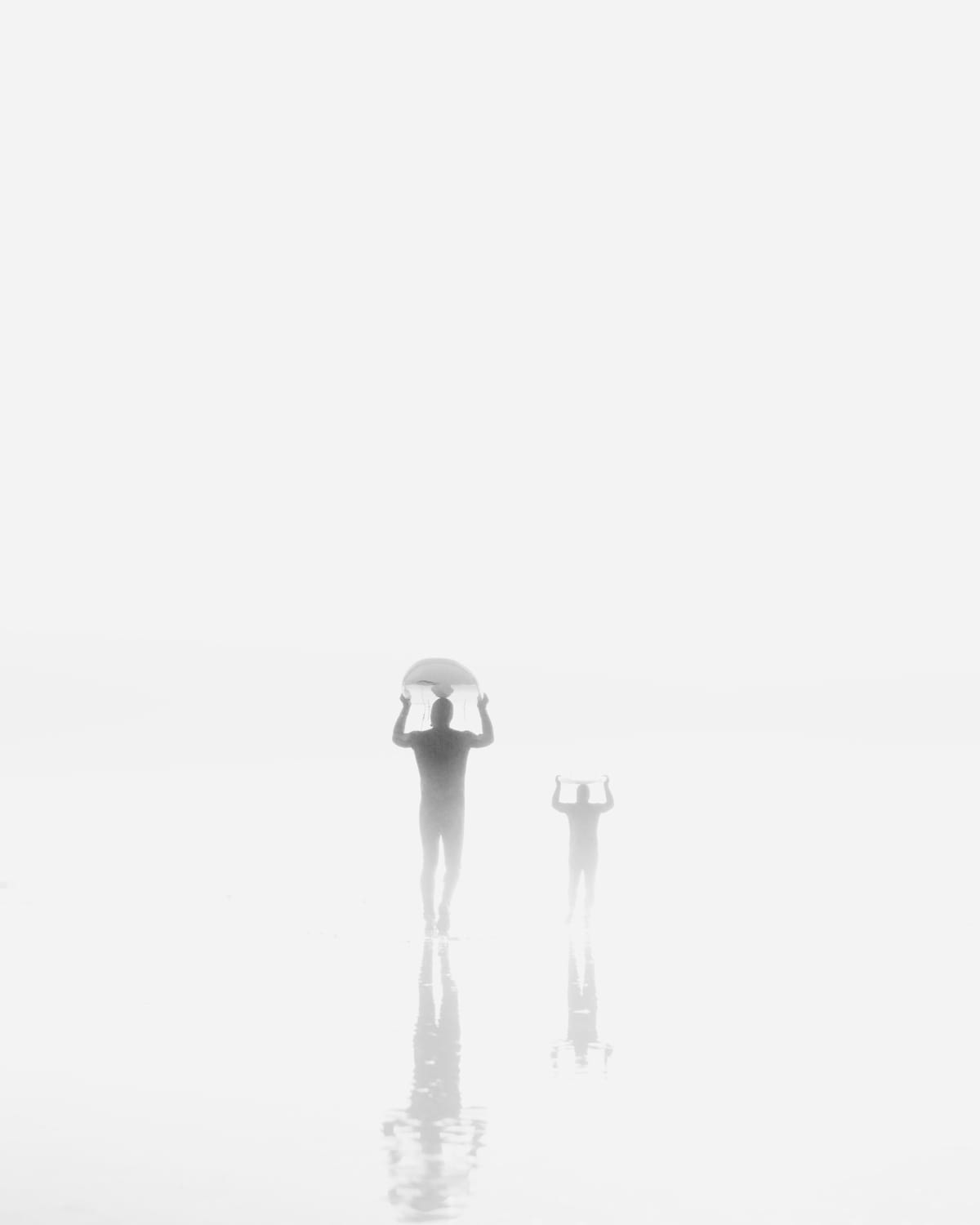 Surfers walking into the fog.