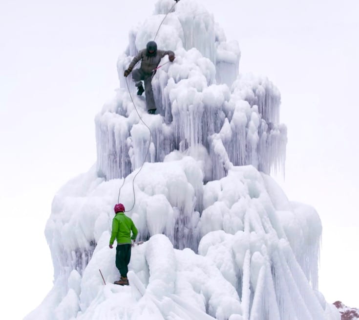 Two men climbing on the ice stupa.