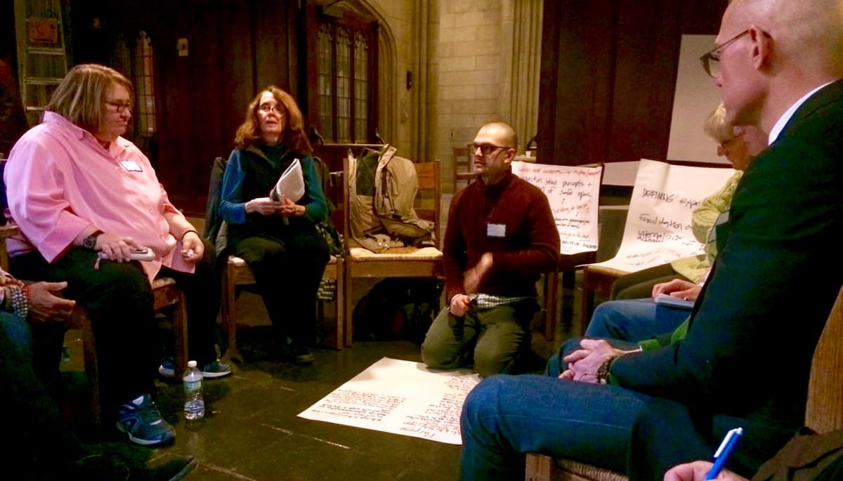 Conference attendees sit in a circle discussing ideas.