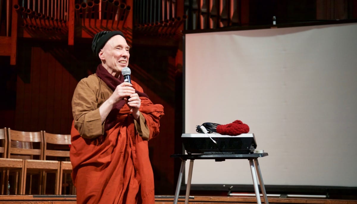 Bhikkhu Bodhi holding a microphone.