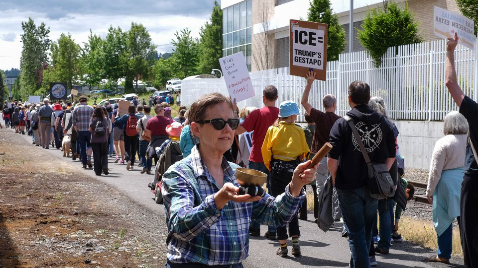 A demonstrator rings a Tibetan singing bowl while activists walk in silence.