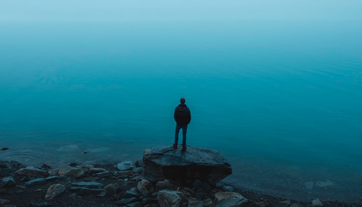 Man standing on rock in front of ocean.