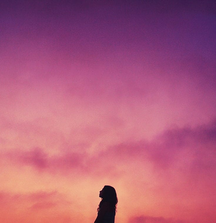 Woman at sunset staring towards the sky.