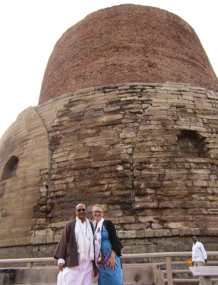 Two people pose with their arms around each other in front of a large temple.