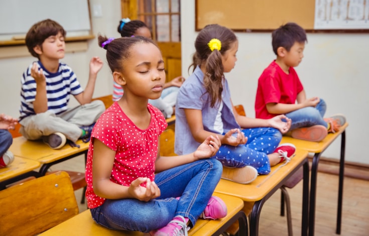 Children meditating on their desks.