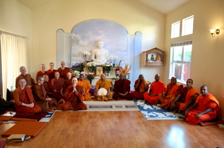 A group of monks and nuns sitting on the floor of a shrine room for an ordination ceremony.
