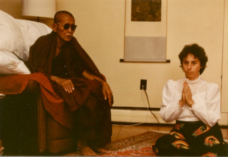 Jacquelline Mandell sits on the floor next to an elder monk, Taungpulu Sayadaw