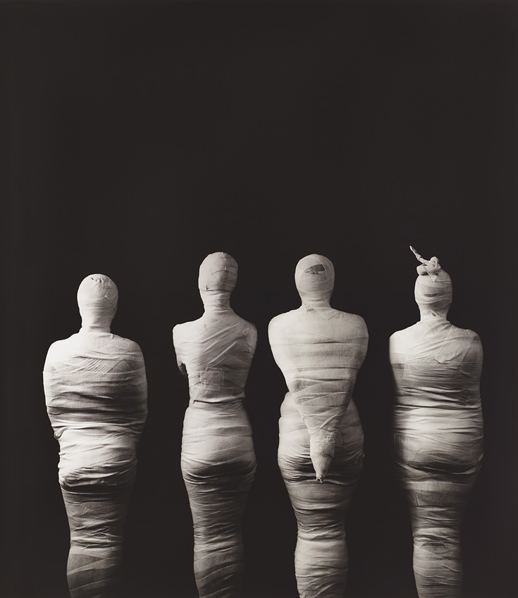 Photo taken from the back with four mummified people.