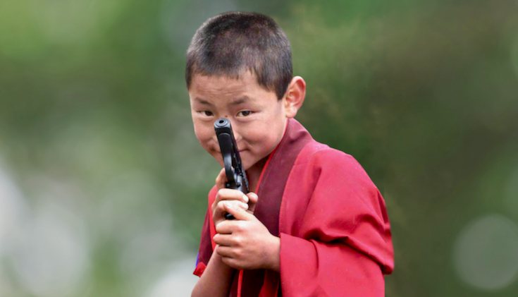 A boy monk holding a gun.