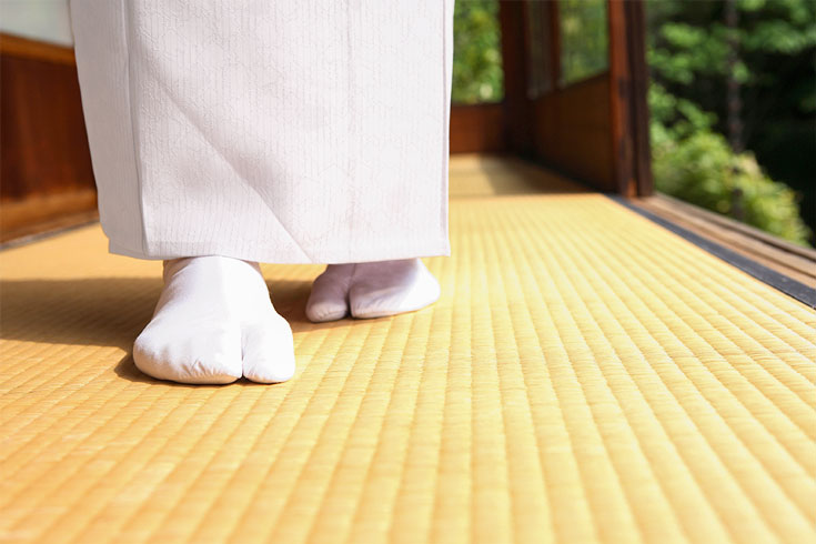 Socked feet walk across a yellow floor.