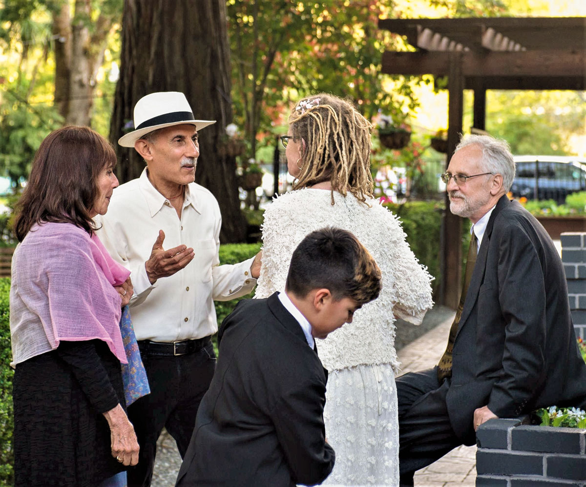 A group of people at a wedding. They are all wearing formal dress.