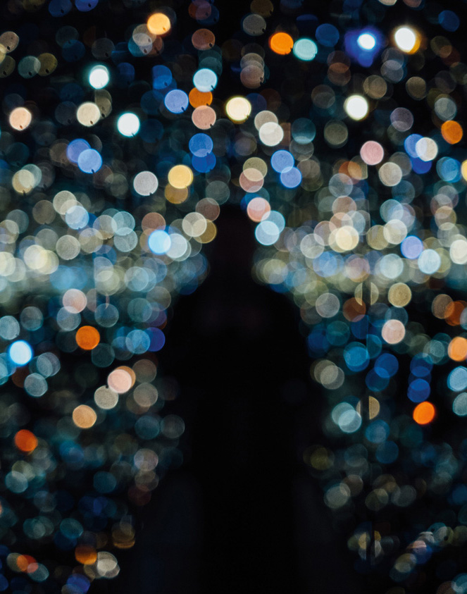 An out of focus photo of a sillhouette with different coloured lights.