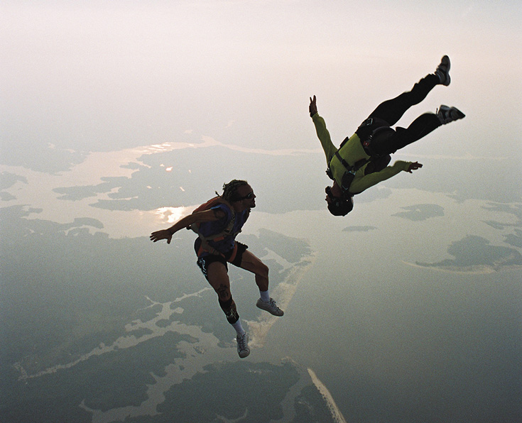 Two people skydiving. One is in the air upside down.