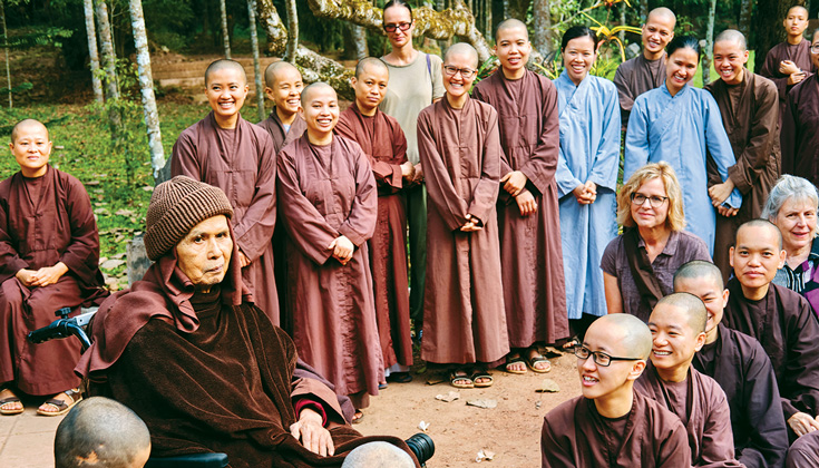 A group of people in purple robes. There are two people with blue robes on the right side. Everyone is smiling.