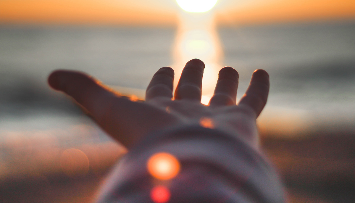 Photo of hand outstretched towards sun