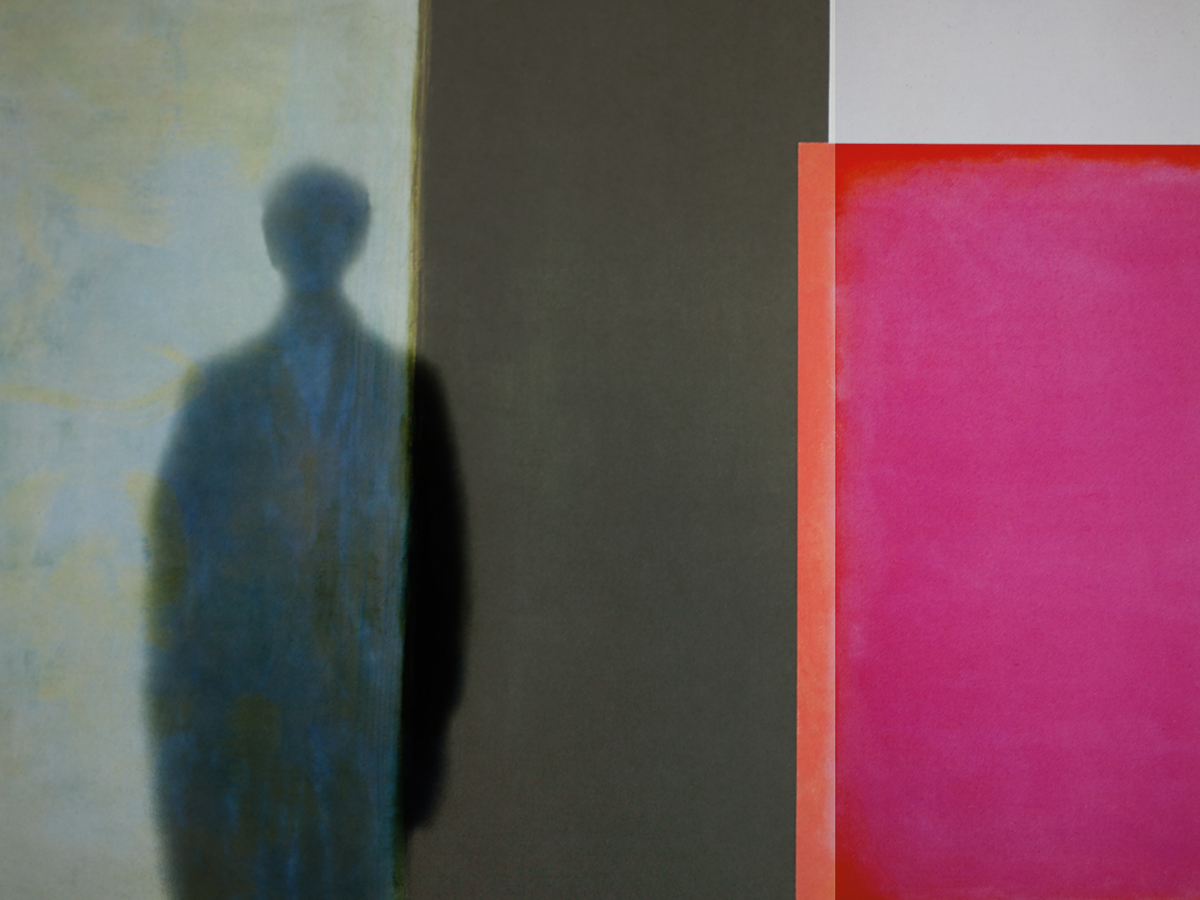 A black shadow of a person against a wall. The wall is half beige, half black, with a pink square on the side.