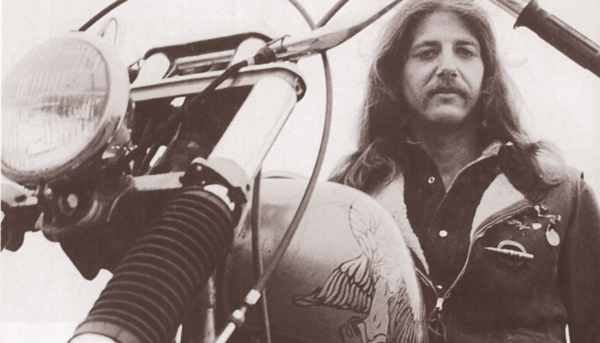 A black and white photo of a man on a motorcycle.