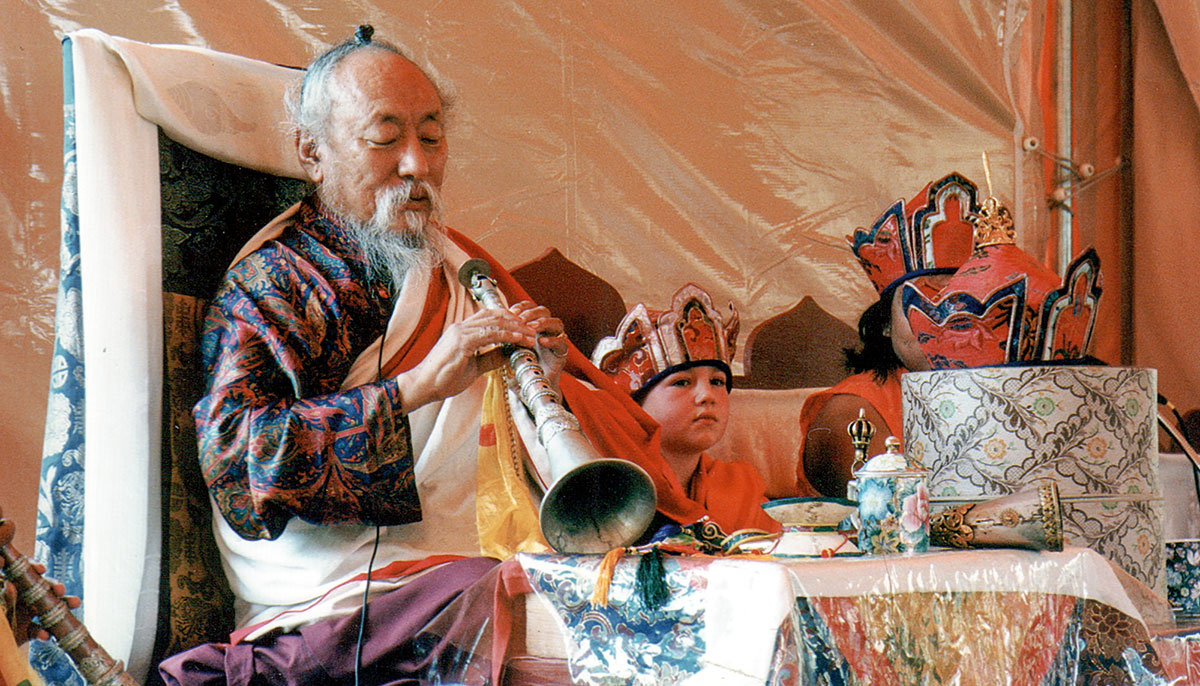 A man with a horn. Children are sitting next to him.