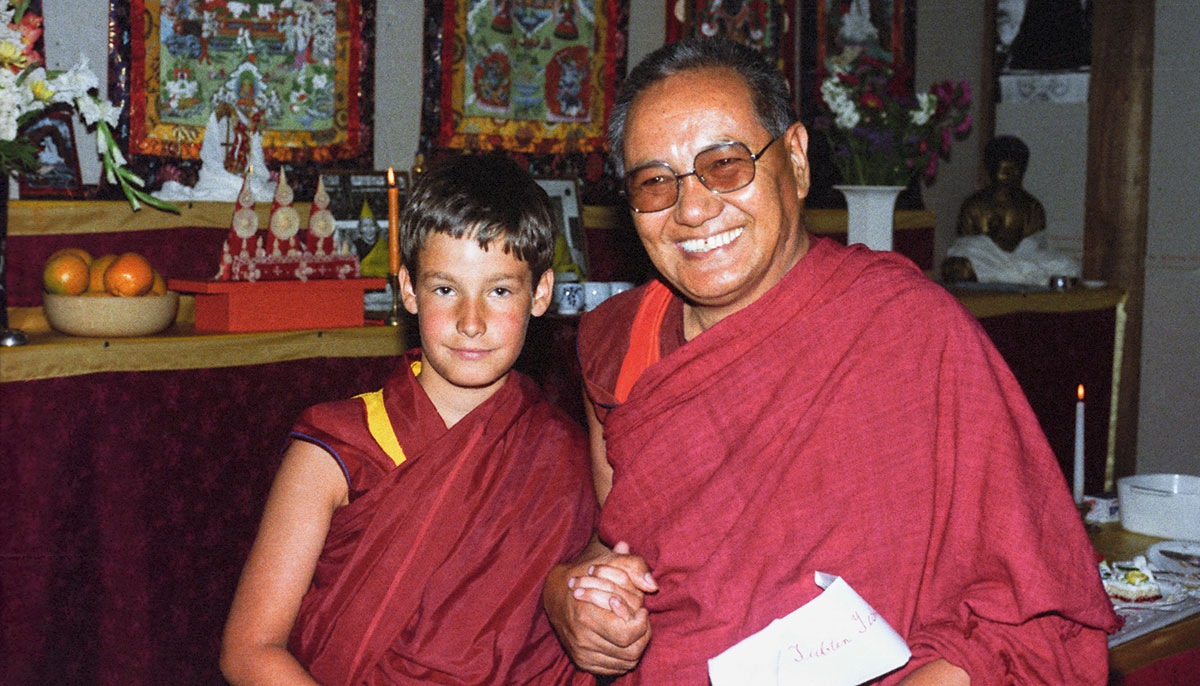 A young boy in monk's robes next to an older man with glasses in monk robes.