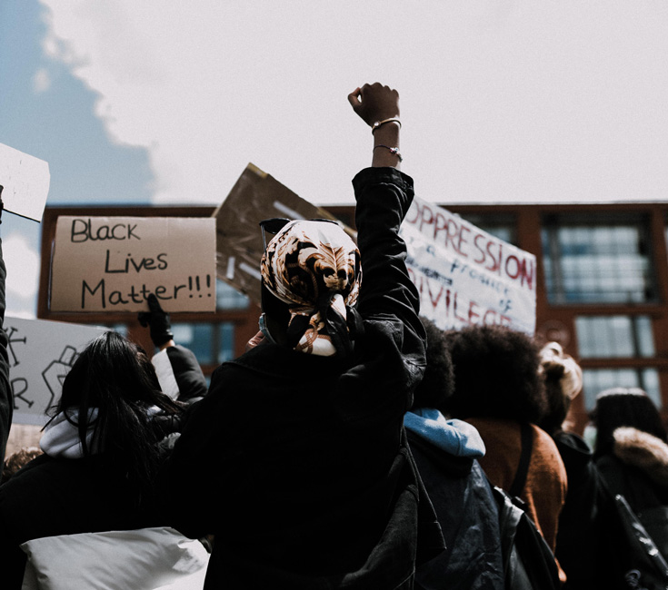 A photo of a person at a protest with signs that read "Black Lives Matter."