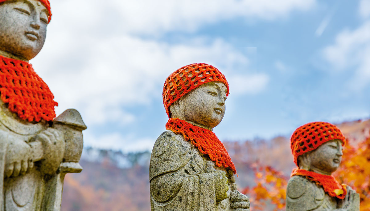 Statues wearing a crocheted red hat and bib.