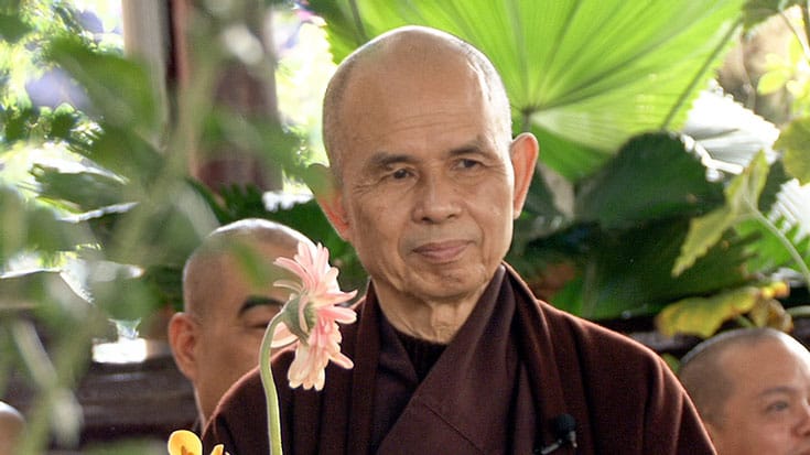 Thich Nhat Hanh holding a flower.