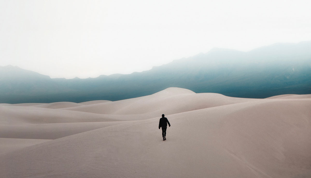 Person walking on cold sand dunes.