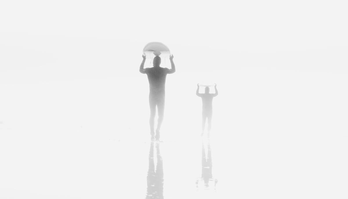 Surfers walking into the fog.